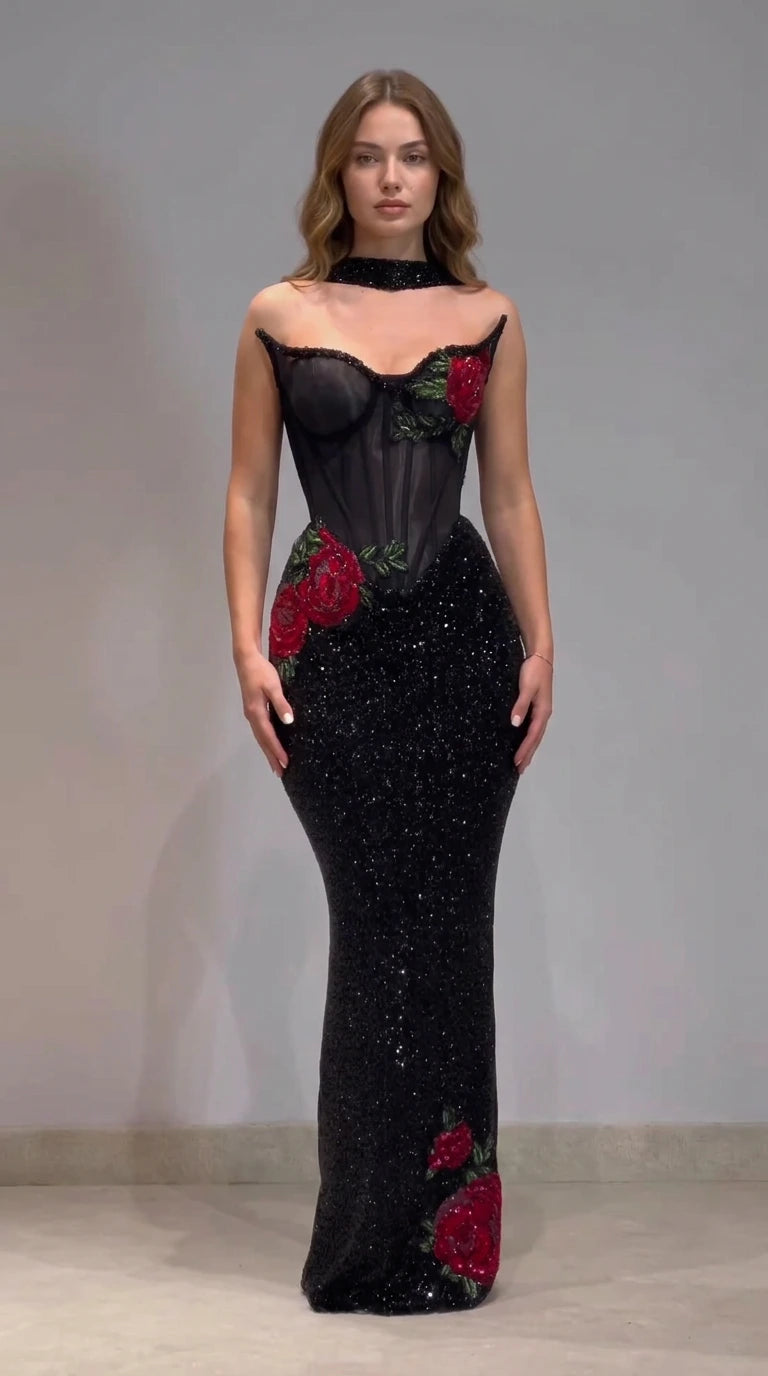 Front view of black corset mermaid evening gown with red rose applique and choker band