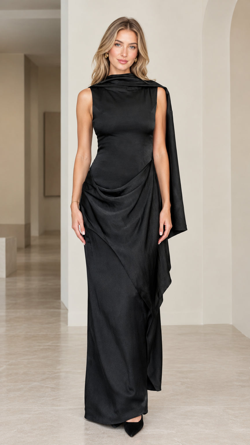 Front full view of woman wearing black sleeveless drape neck evening maxi dress with cascading shoulder sash
