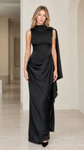 Front full view of woman wearing black sleeveless drape neck evening maxi dress with cascading shoulder sash