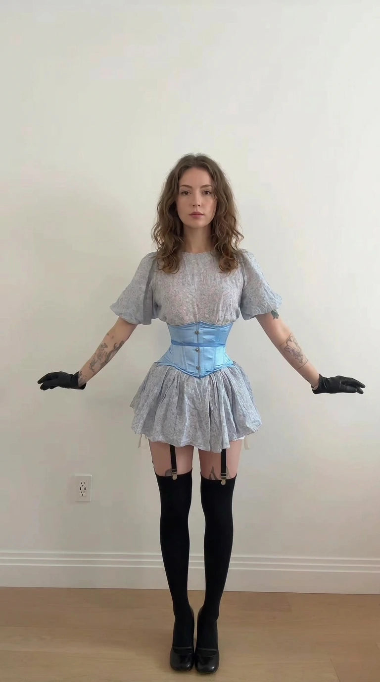 Front view of model wearing light blue floral puff sleeve mini dress with matching lace-up corset belt