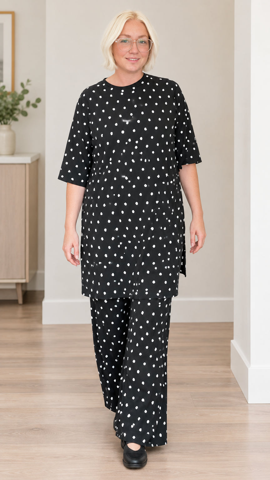 Front full view of woman wearing black polka dot tunic top and wide-leg pants set