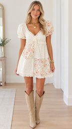 Front view of model wearing white floral patchwork puff sleeve mini dress with boots