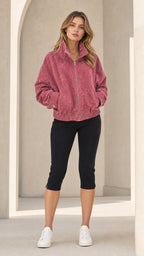 Front view of woman wearing Dusty Rose textured zip-up bomber jacket with black capri leggings