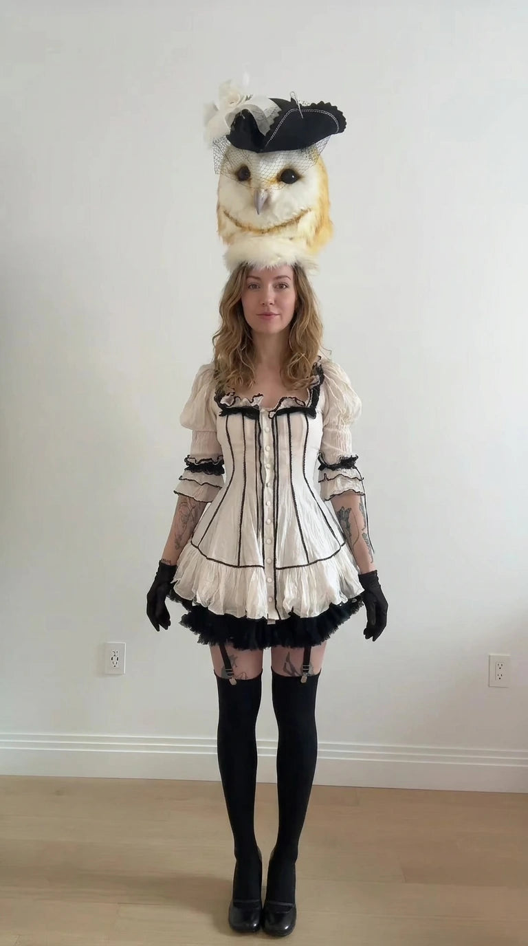Front full-length view of white gothic lolita mini dress with black contrast piping and ruffled hem