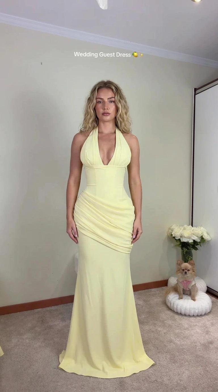 Front view of woman wearing pastel yellow plunge halter ruched maxi dress