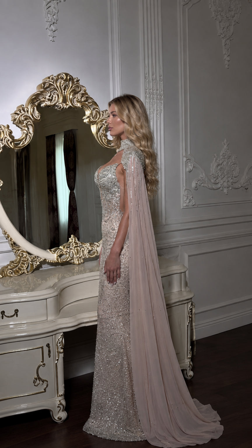 Side profile of woman in champagne floor-length embellished dress with flowing cape