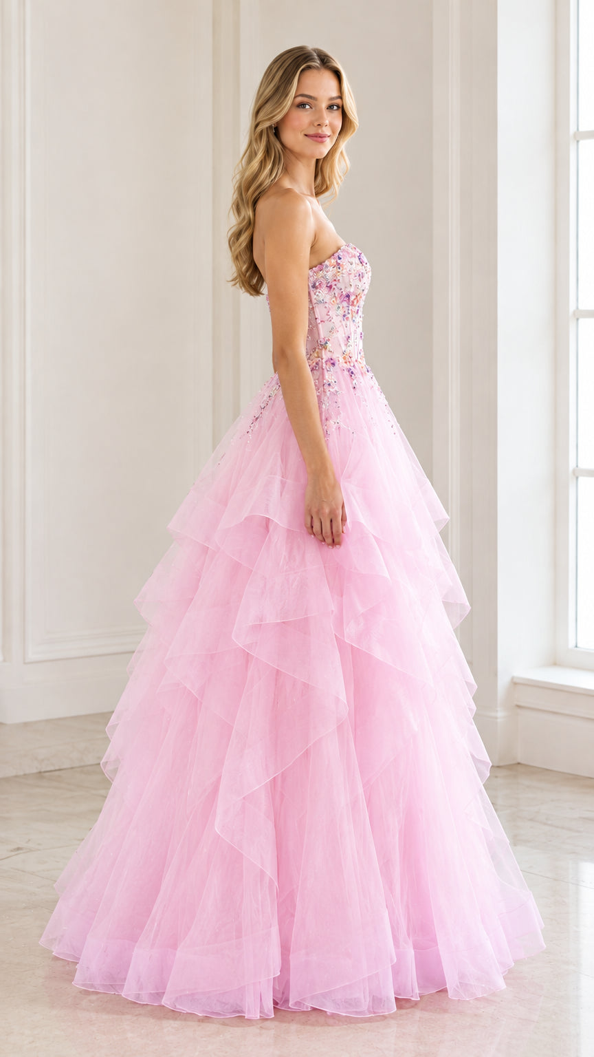 Side angle of woman in a pink beaded strapless ball gown with voluminous tiered skirt