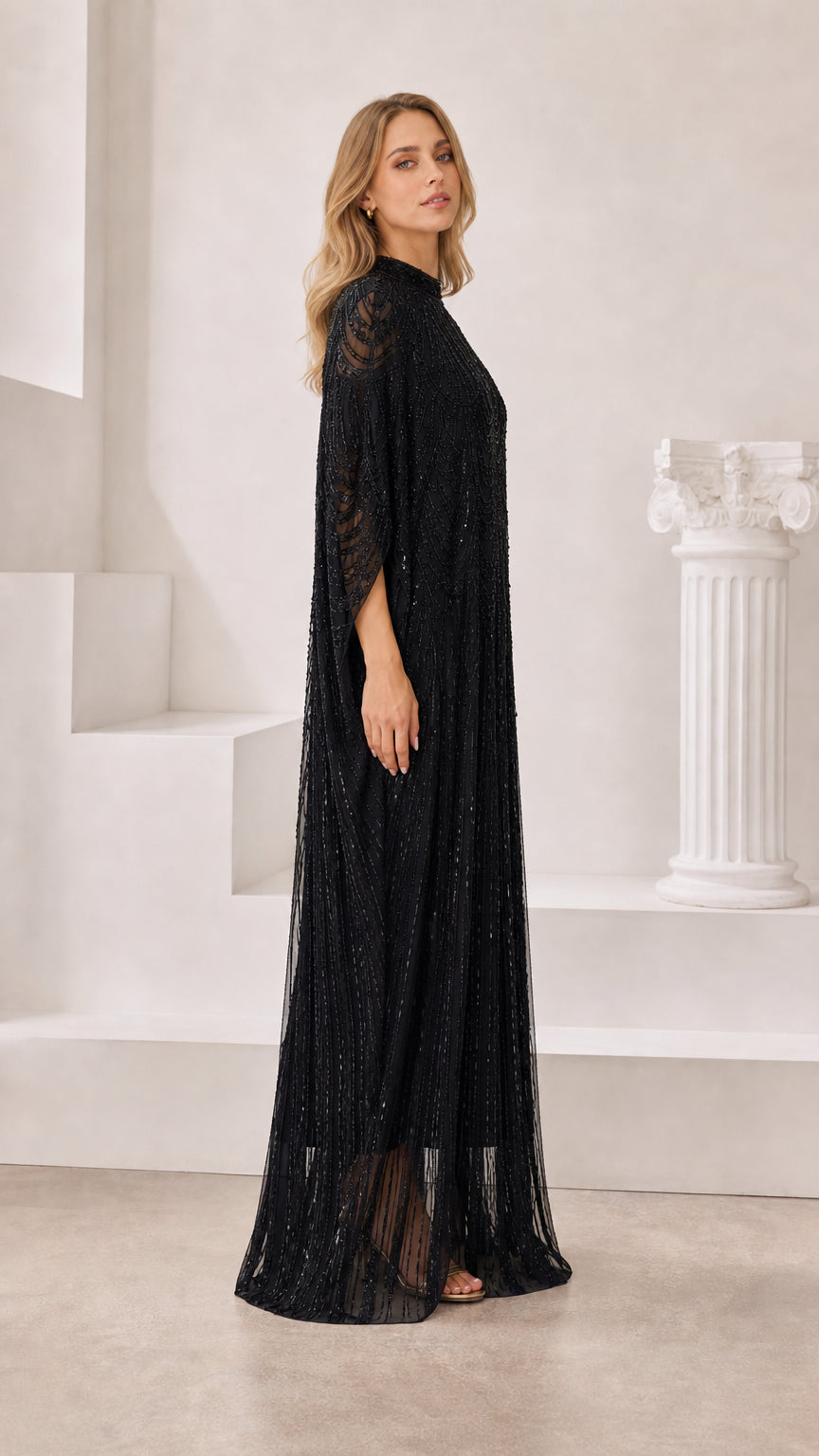 Side three-quarter view of black beaded cape evening gown