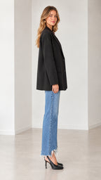 Side profile of a model wearing a black relaxed-fit single-breasted blazer with jeans