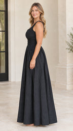 Side profile of model wearing black sleeveless maxi dress with smocked bodice