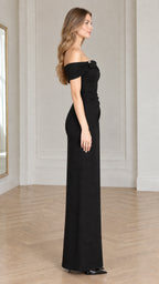 Side profile view of model wearing the black off-the-shoulder column gown