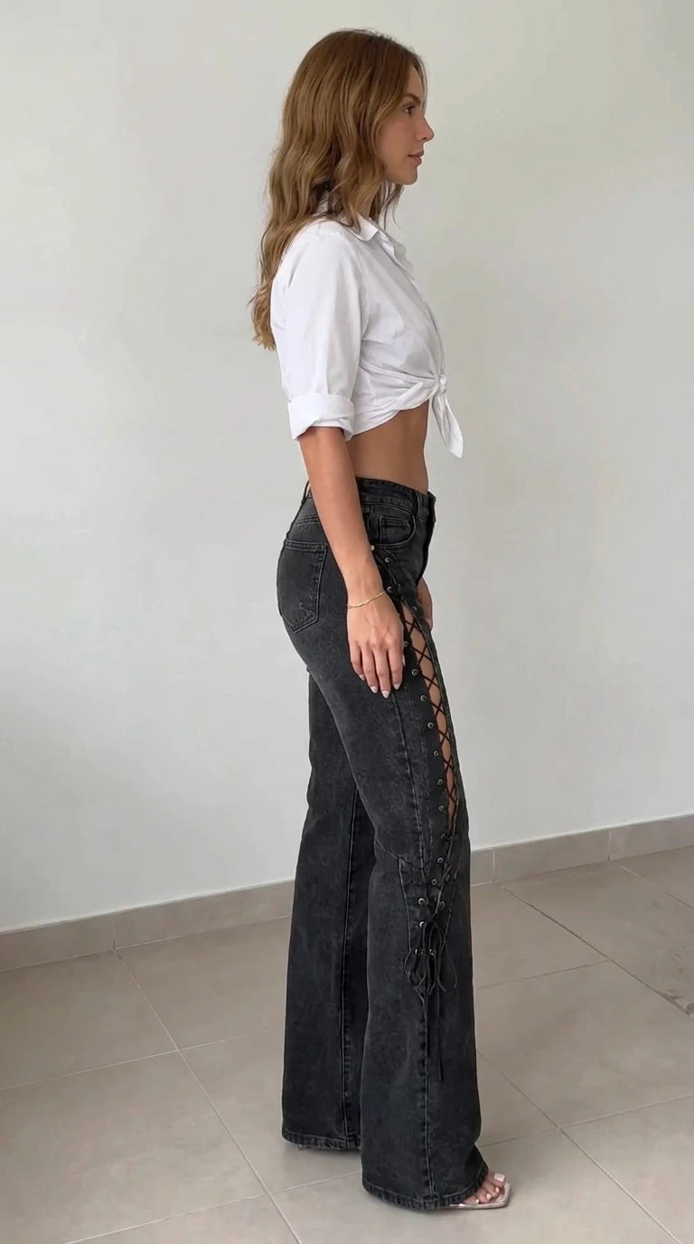 Side profile view of model wearing washed black flared jeans showcasing outer thigh criss-cross lacing