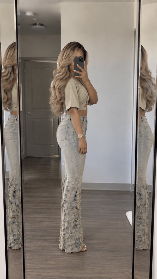 Side profile view showing beige wrap crop top and fringed light-wash flare pants