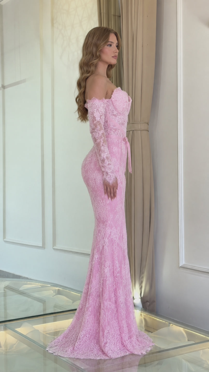 Side profile view of a model wearing a pink lace trumpet evening dress with ribbon waist sash