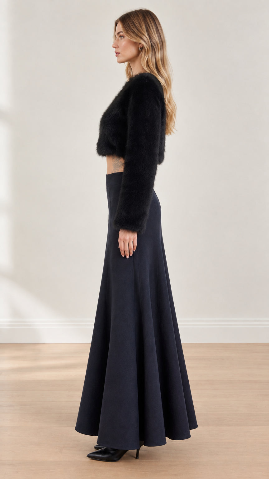 Side profile of model wearing black fuzzy cropped top and high-waisted maxi skirt