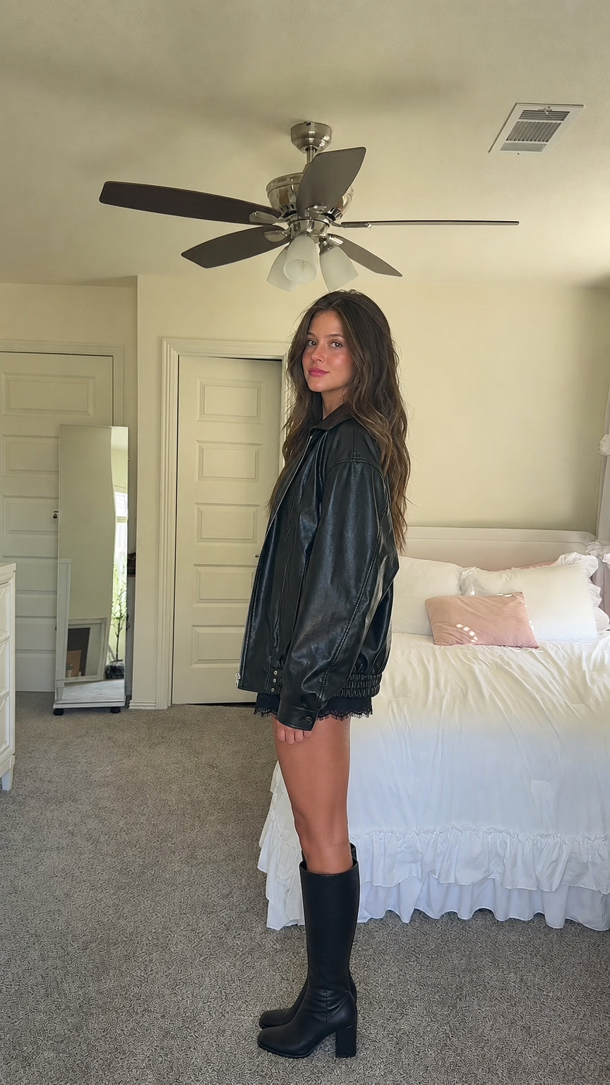 Side profile of model in black oversized faux leather jacket