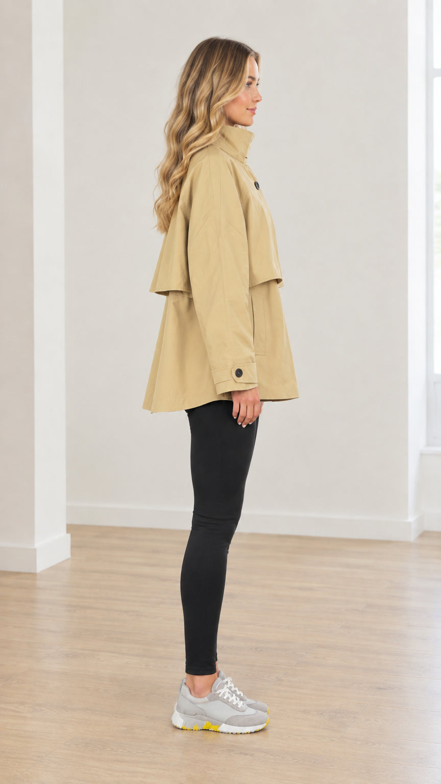 Side profile view of woman wearing khaki short trench jacket showing flared fit and storm flap