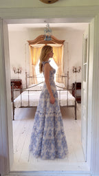Side profile view of blue and white floral corset maxi dress showing tiered A-line skirt