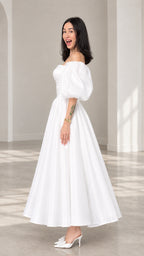 Side profile view of a woman wearing a white corset-bodice tea-length evening dress