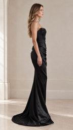 Side profile view of black strapless embroidered corset gown with draped skirt