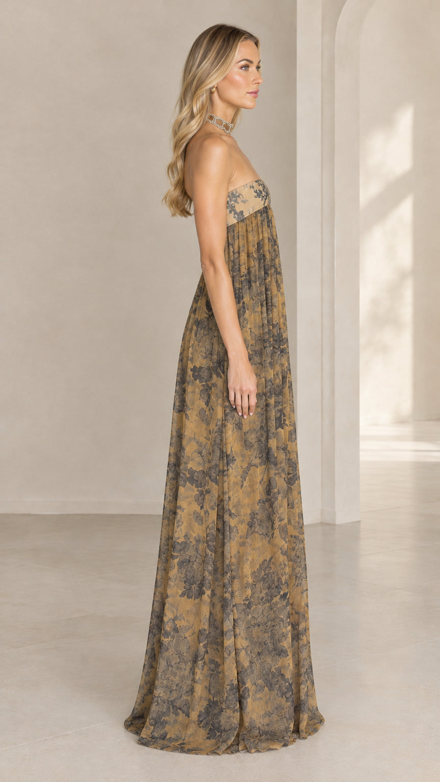 Side profile view of woman wearing strapless golden tan floral maxi dress