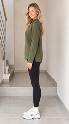 Side view of model wearing olive green relaxed knit sweater highlighting side slit hem