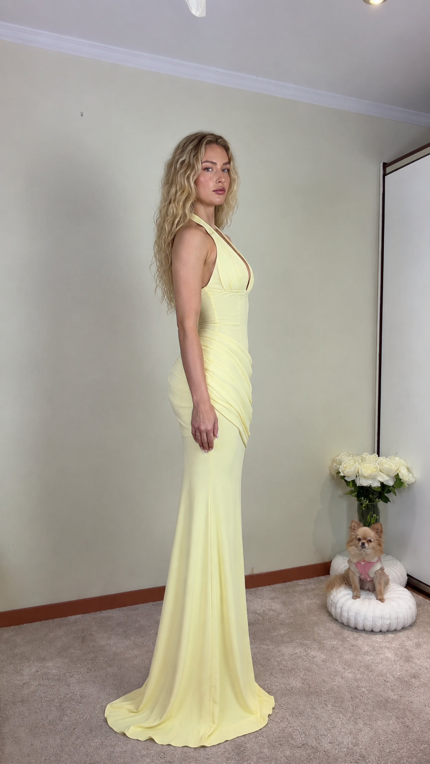 Side profile view of pastel yellow halter evening gown showing fitted silhouette