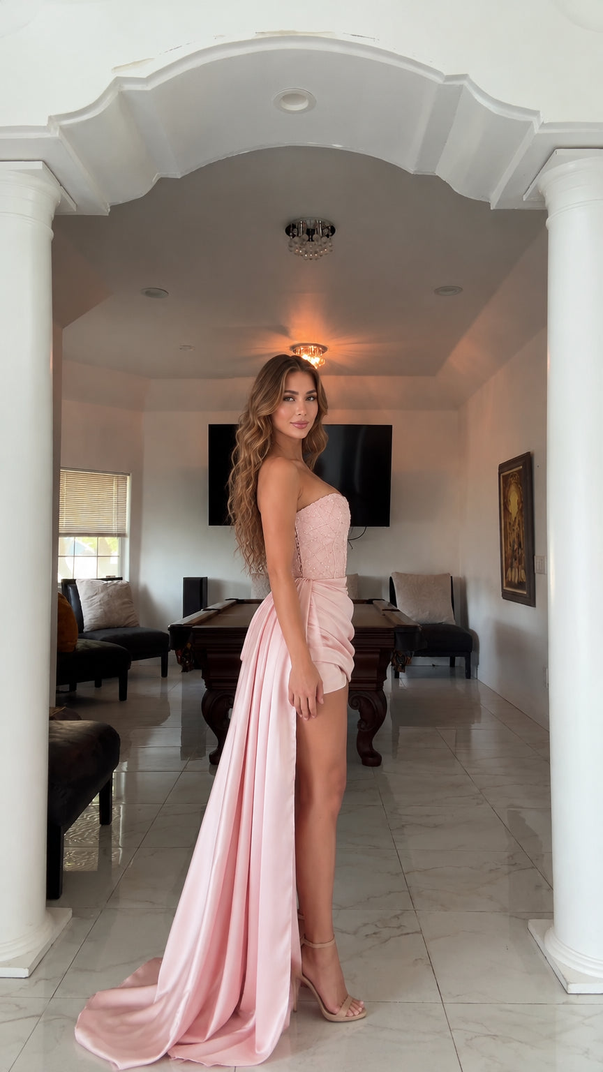 Side angle of woman wearing blush pink strapless dress with sweeping floor train