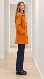 Side angle view of woman modeling cognac mid-length coat