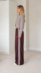 Side profile view of model wearing grey cardigan and brown side-striped track pants