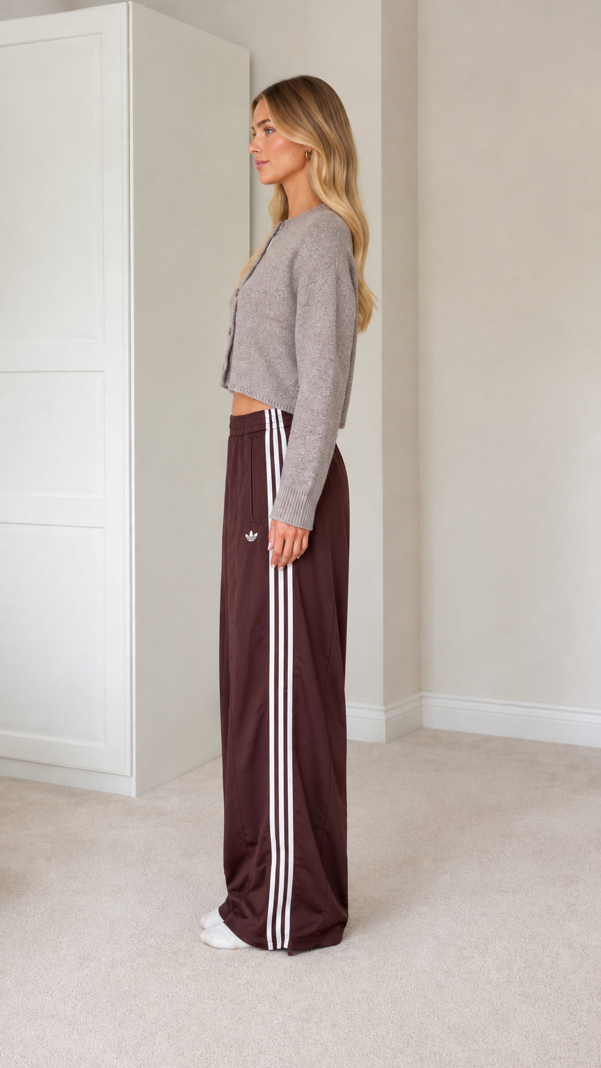 Side profile view of model wearing grey cardigan and brown side-striped track pants