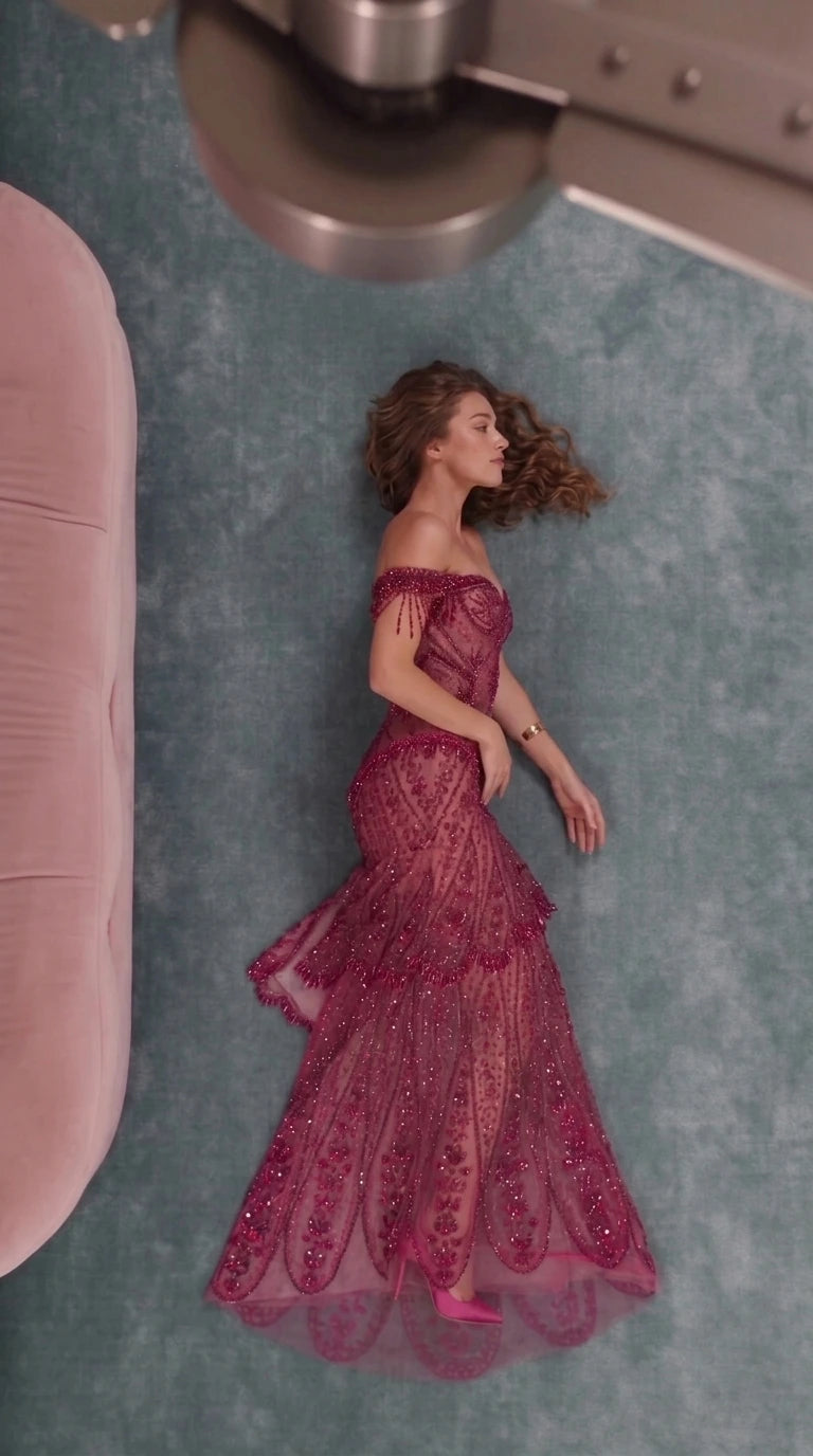 Side angled view of burgundy beaded tiered evening gown on model