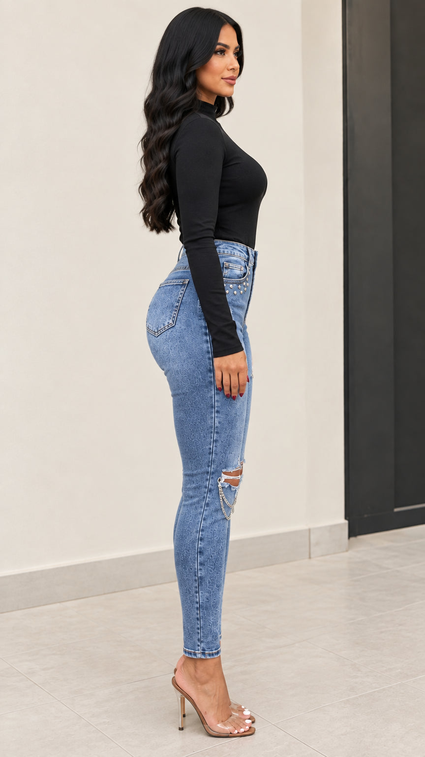 Side profile view of high-waisted blue ripped skinny jeans with chain hardware