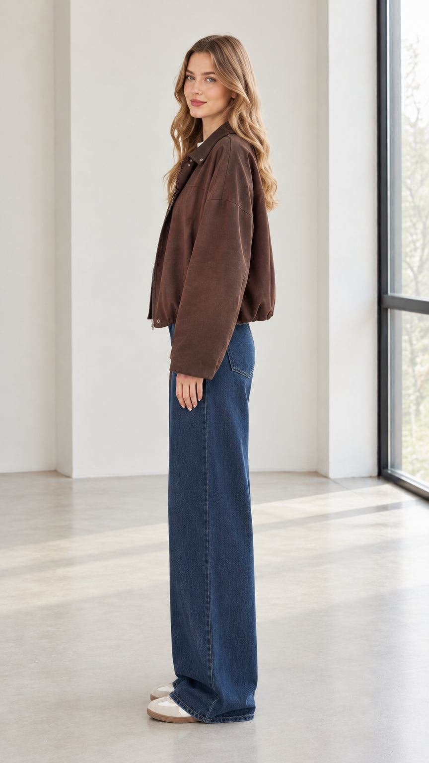 Side profile view of woman wearing brown casual jacket and blue denim trousers
