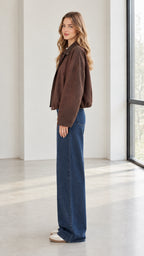 Side profile view of woman wearing brown casual jacket and blue denim trousers