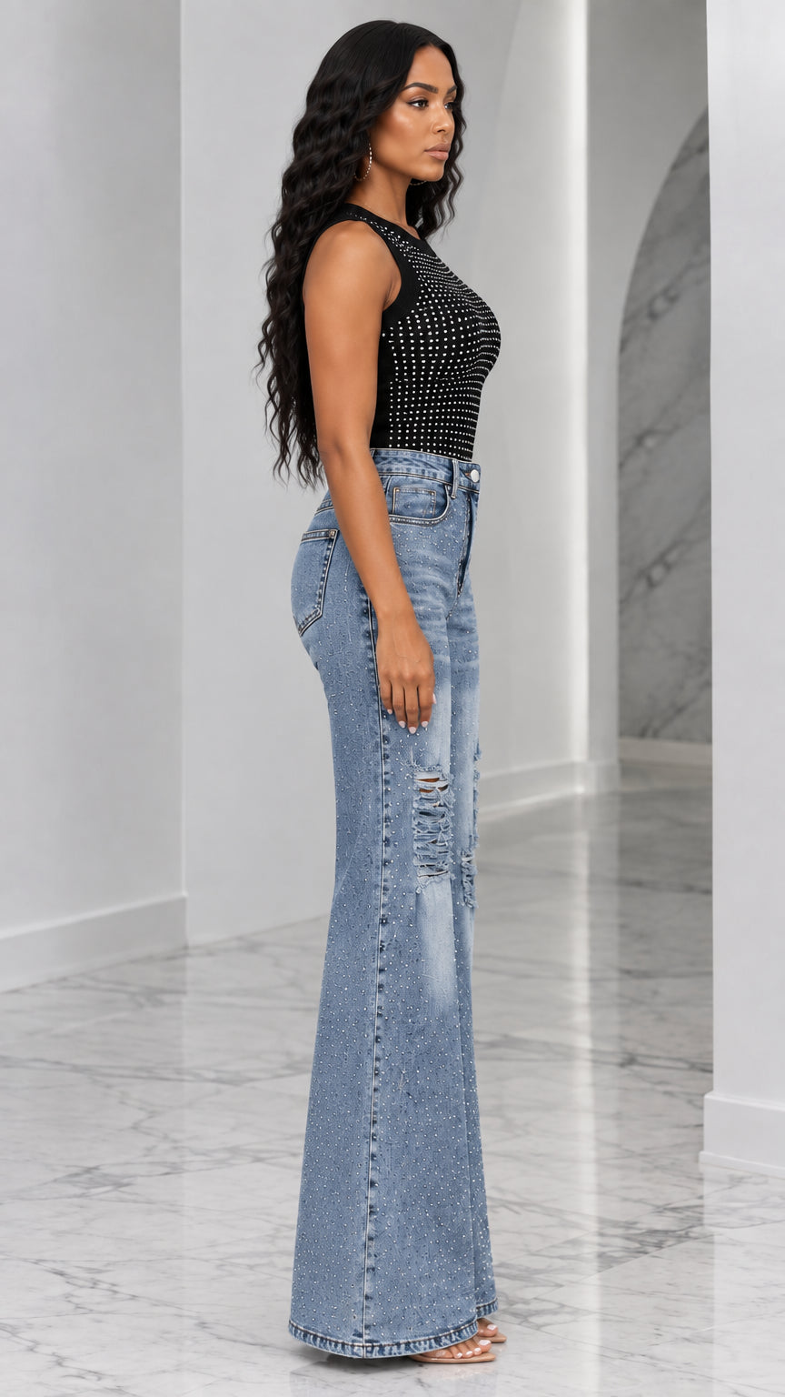 Side profile view of woman wearing black studded sleeveless top and high-waisted flare jeans