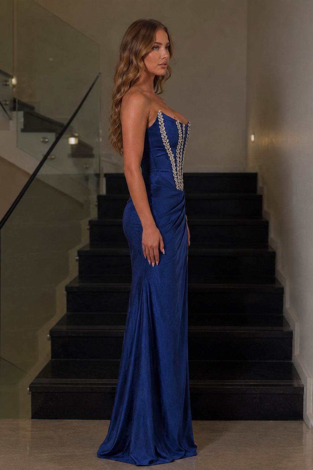 Side view of royal blue satin corset evening gown with high leg slit