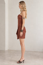 Side profile view of strapless rust brown mini dress showing gathered waist detail