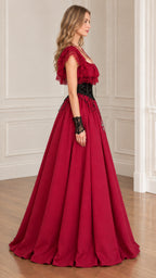 Side profile view of woman modeling burgundy ruffle lace maxi ball gown