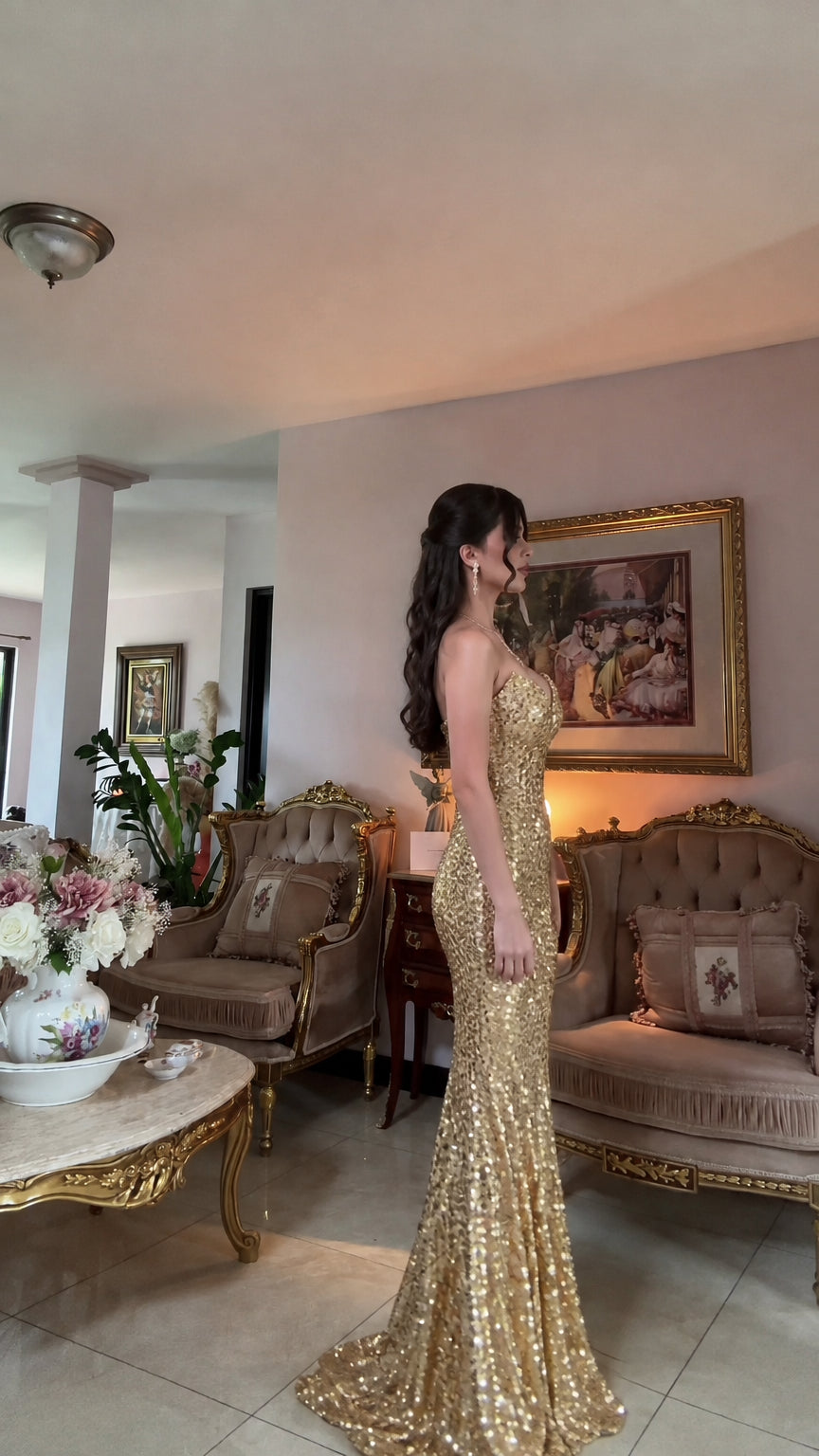 Side view of woman in fitted gold sequin mermaid gown showing floor-length train