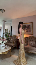 Side view of woman in fitted gold sequin mermaid gown showing floor-length train