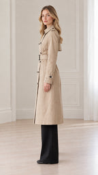 Side profile view of women's classic beige trench coat paired with wide-leg trousers