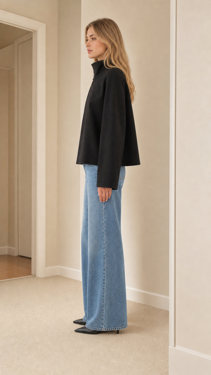Side view of model wearing black high neck cropped coat showing profile silhouette
