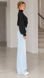 Side profile view of model wearing black cropped blouson knit sweater
