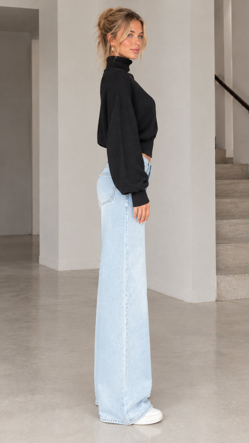 Side profile view of model wearing black cropped blouson knit sweater