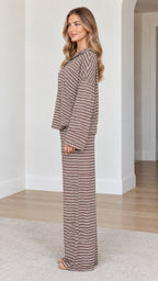 Side profile of model wearing brown striped knit lounge set with fluid wide leg trousers
