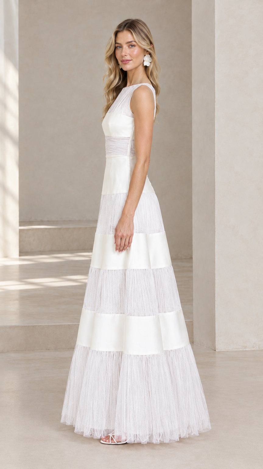 Side profile view of model wearing white tiered A-line formal maxi gown