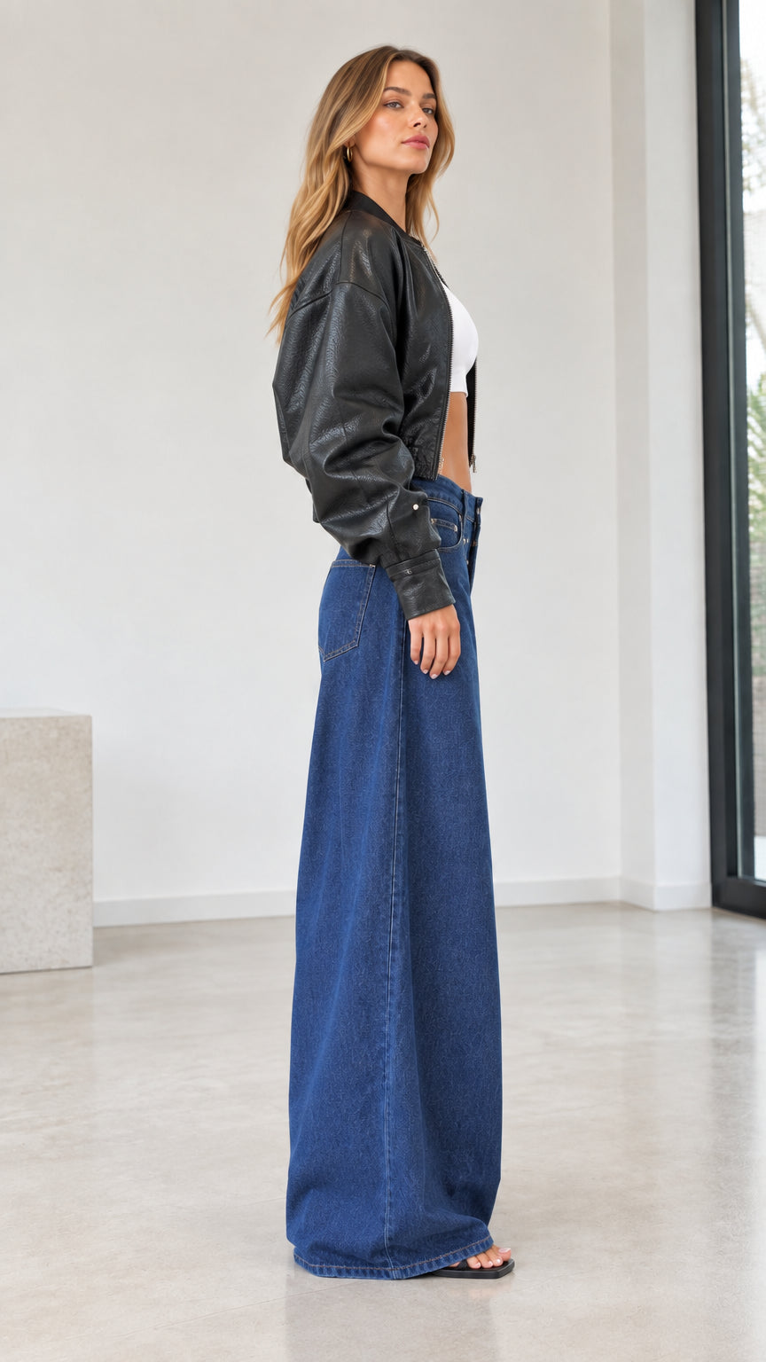 Side profile view of model wearing black cropped bomber jacket and wide leg denim trousers