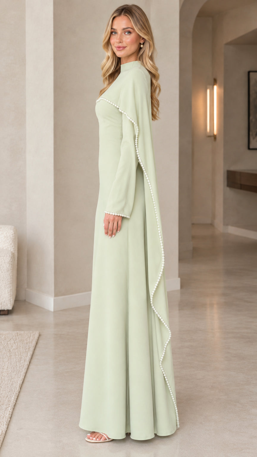 Side profile of woman wearing sage green pearl-trimmed cape sleeve formal dress