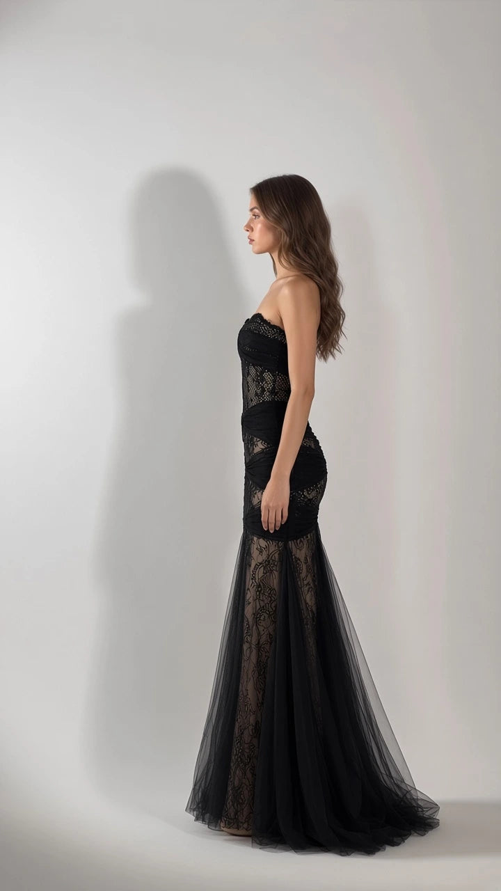 Side profile view of woman modeling black strapless ruched lace mermaid formal dress